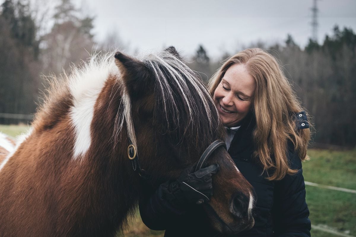 En glad kvinna sköter om sin häst.