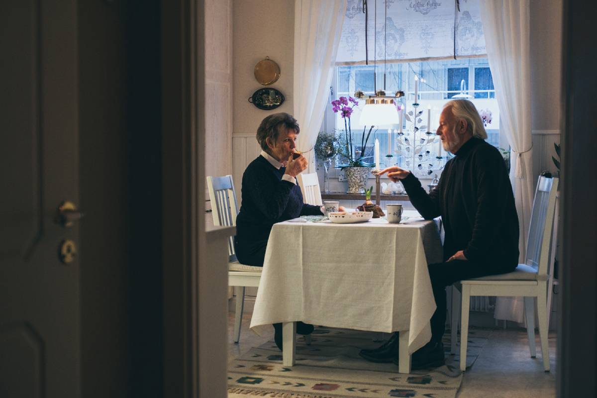 Ett äldre par sitter vid ett bord och fikar.