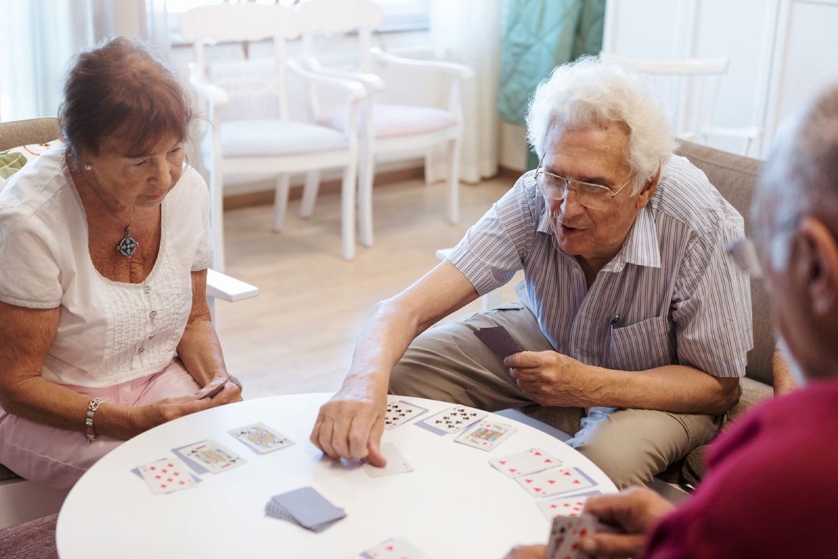 Tre äldre personer spelar kort.
